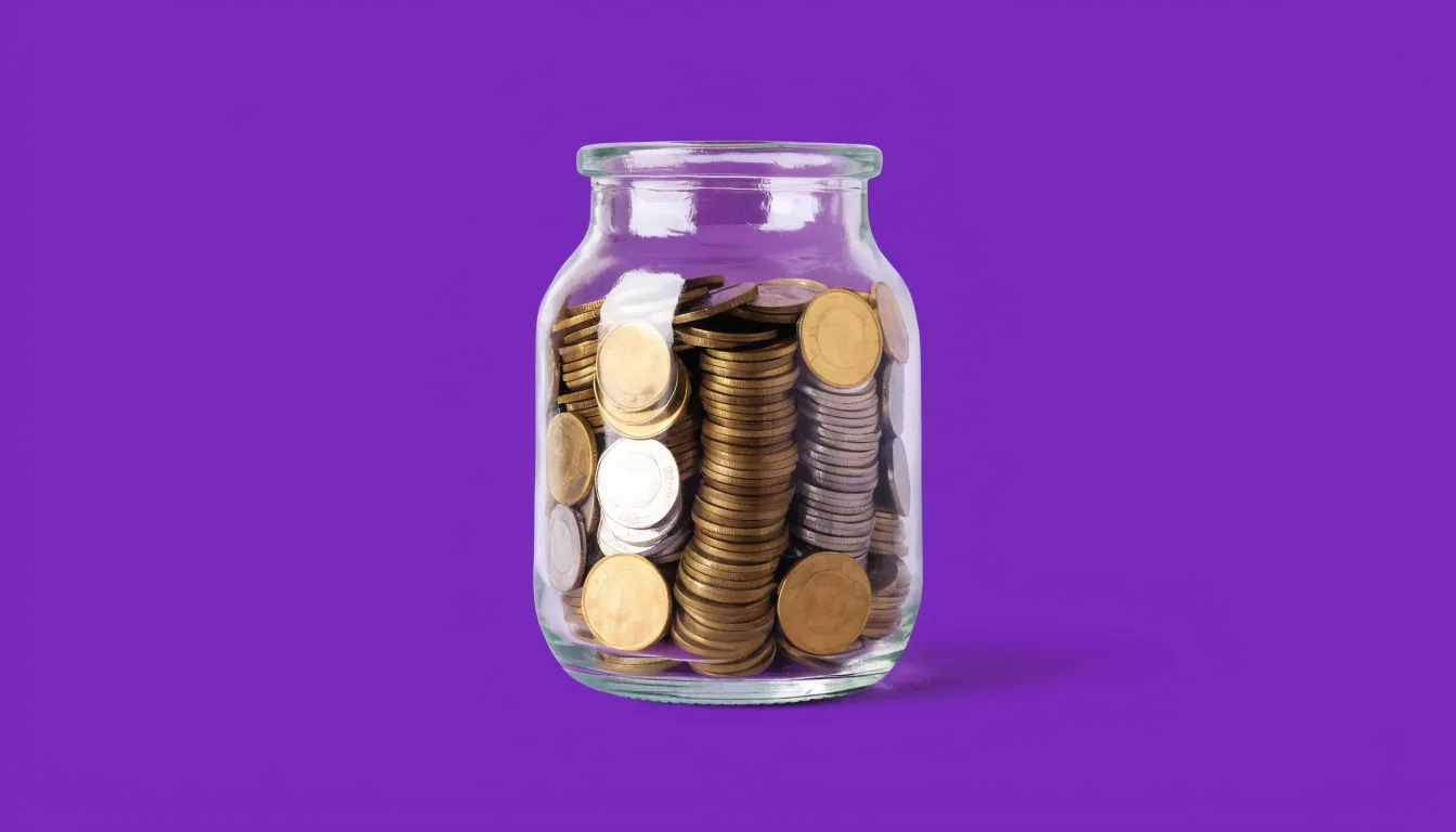 A clear glass jar filled with coins on a solid purple background.